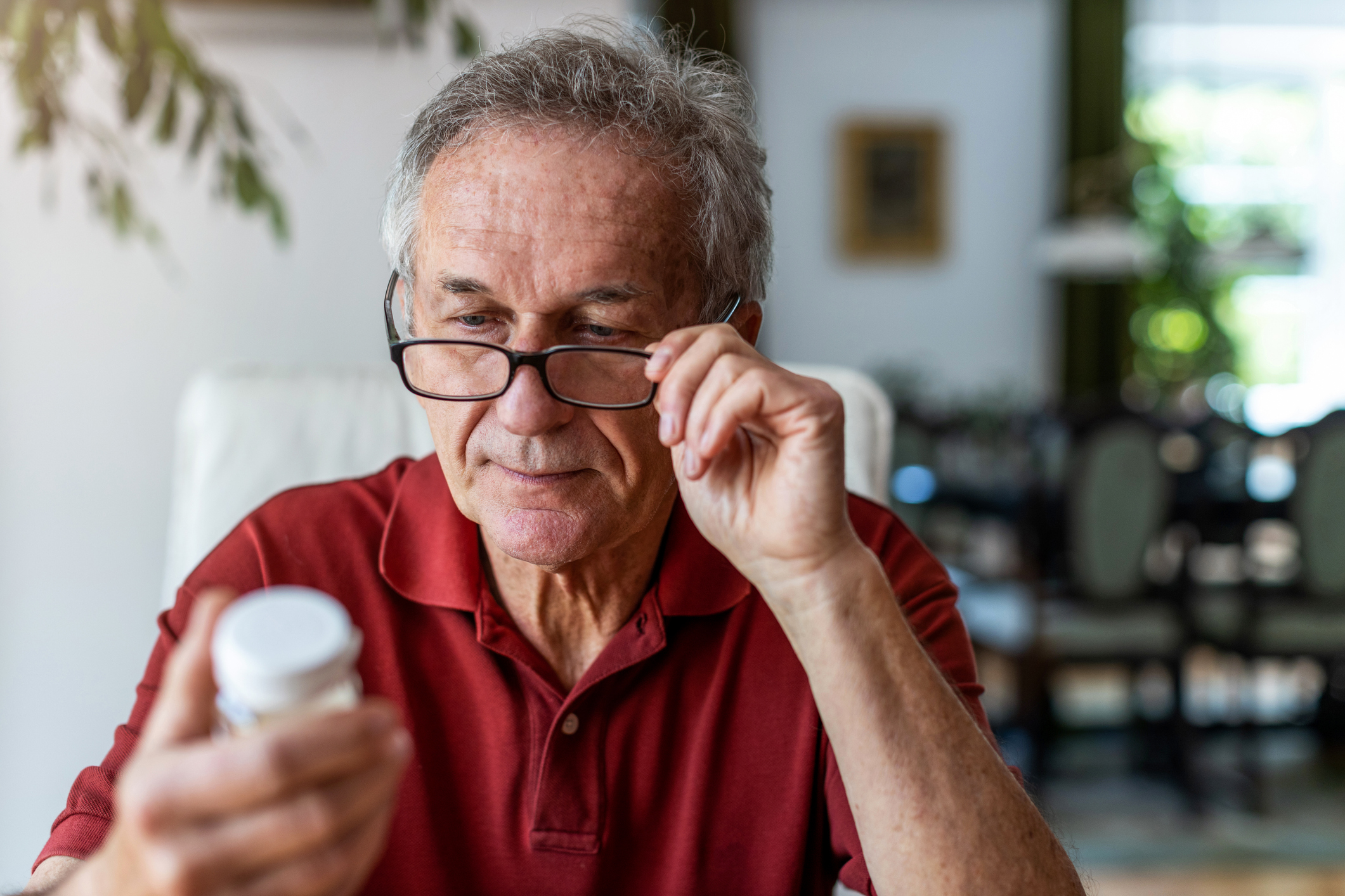 elderly man trying to understand his prescription medication vile. medication mismanagement concept image 