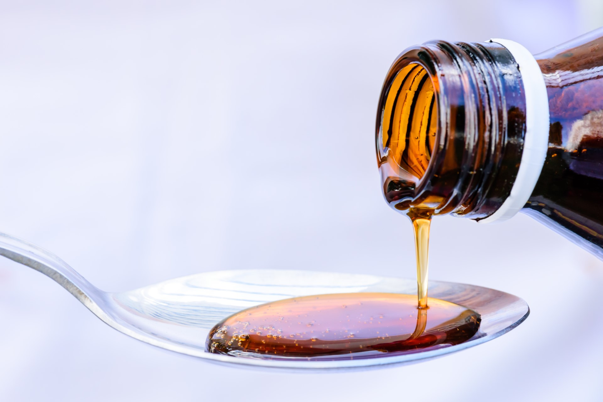 cough syrup poured on spoon - most commonly abused OTC medications concept