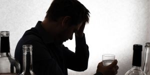 Man drinking water after a night of consuming alcohol and experiencing Alcohol Withdrawal Symptoms